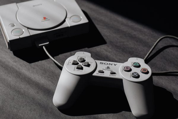 photo of play station game console and remote controller
